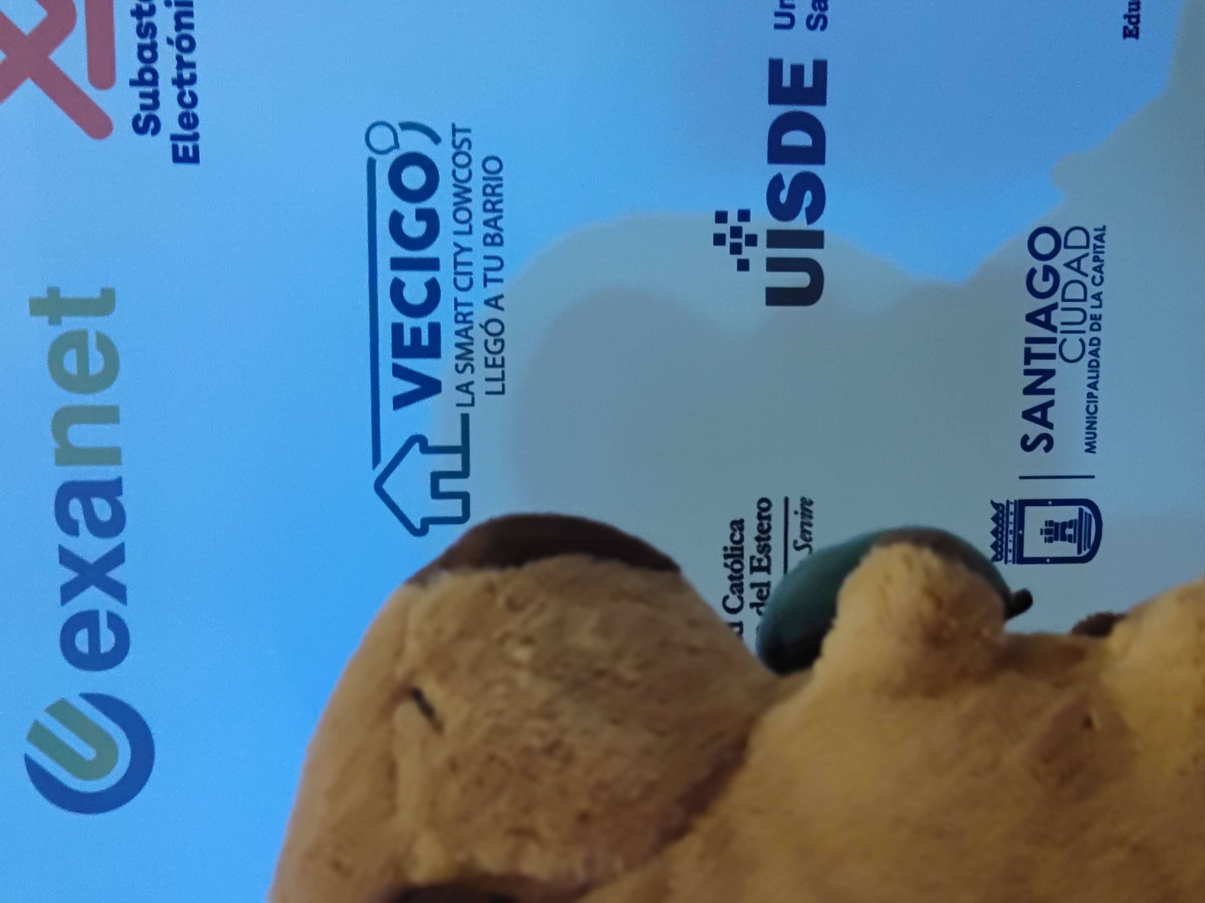 Capi junto al logo de VeciGo en el panel de Smart City 2026 Santiago del Estero